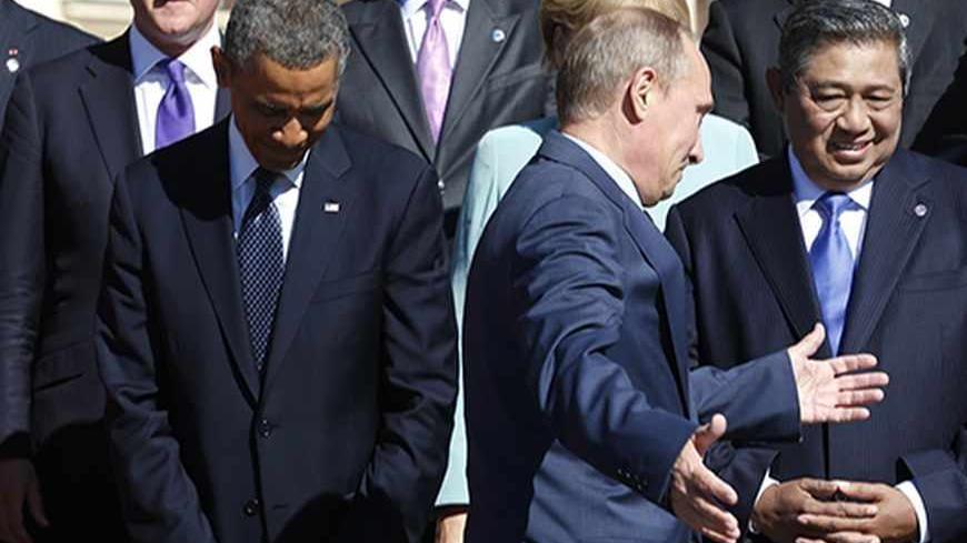 Russian President Vladimir Putin holds out his arms as he walks past U.S. President Barack Obama (L) during a group photo at the G20 Summit in St. Petersburg September 6, 2013.  Above Obama is British Prime Minister David Cameron. At right is Indonesian President Susilo Bambang Yudhoyono.   REUTERS/Kevin Lamarque  (RUSSIA - Tags: BUSINESS POLITICS) - RTX139JC