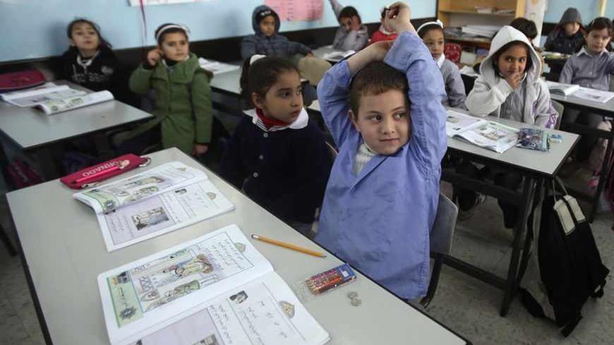 Palestinian first-graders sit with their schoolbooks during class in the West Bank city of Ramallah February 4, 2013. Israelis and Palestinians depict each other in schoolbooks as an enemy and largely deny their adversary's history and existence, according to a U.S. government-funded study published on Monday. REUTERS/Mohamad Torokman (WEST BANK - Tags: EDUCATION POLITICS) - RTR3DCH4