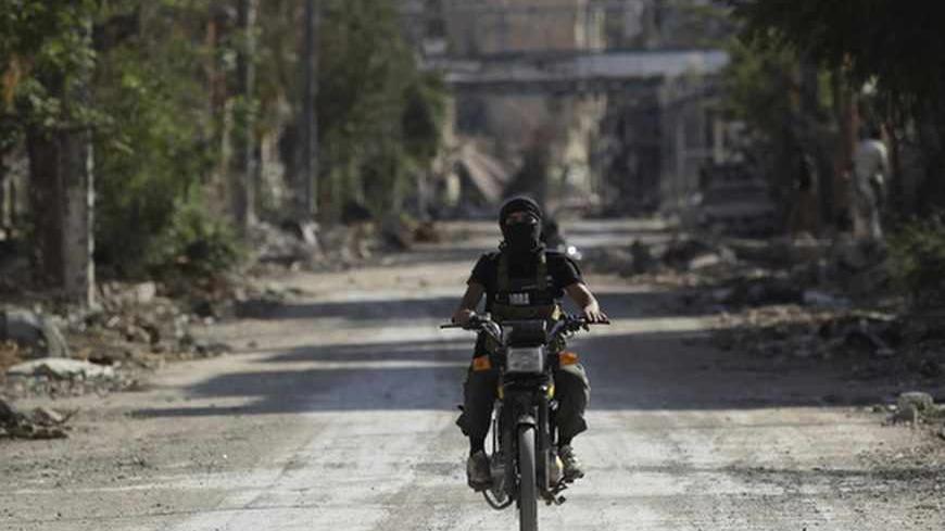 A fighter from the Islamist Syrian rebel group Jabhat al-Nusra rides a motorcycle along a deserted street in Deir al-Zor August 17, 2013. Picture taken August 17, 2013. REUTERS/Khalil Ashawi (SYRIA - Tags: POLITICS CIVIL UNREST CONFLICT) - RTX12PKS