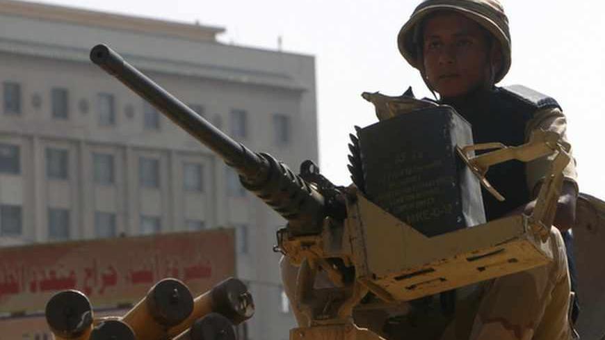 An Egyptian army soldier guards with an armoured personnel carrier (APC) near Tahrir Square in Cairo August 19, 2013. Suspected Islamist militants killed at least 24 Egyptian policemen on Monday in the Sinai peninsula, where attacks on security forces have multiplied since the army overthrew President Mohamed Mursi on July 3. REUTERS/Mohamed Abd El Ghany  (EGYPT - Tags: POLITICS CIVIL UNREST) - RTX12QU2