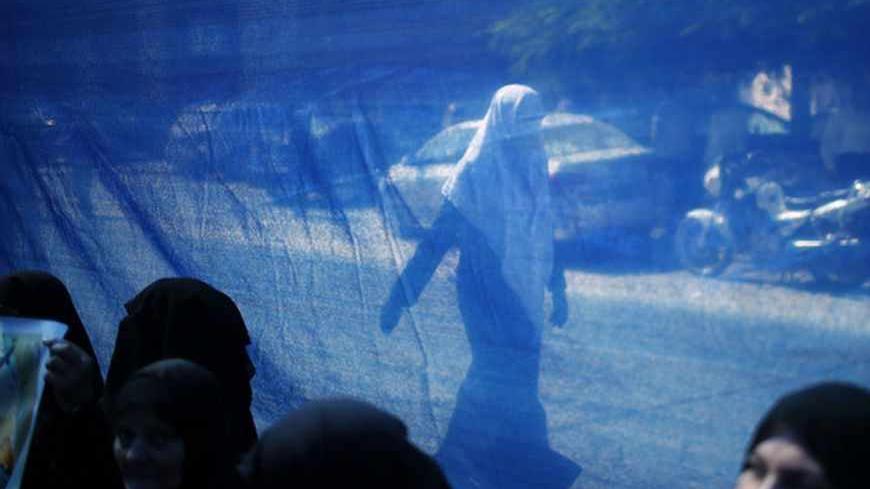 A woman is seen through a fabric sheet as she walks past a rally calling for the release of Palestinian prisoners from Israeli jails, in Gaza City September 2, 2013.  REUTERS/Mohammed Salem (GAZA - Tags: POLITICS CIVIL UNREST) - RTX134LM