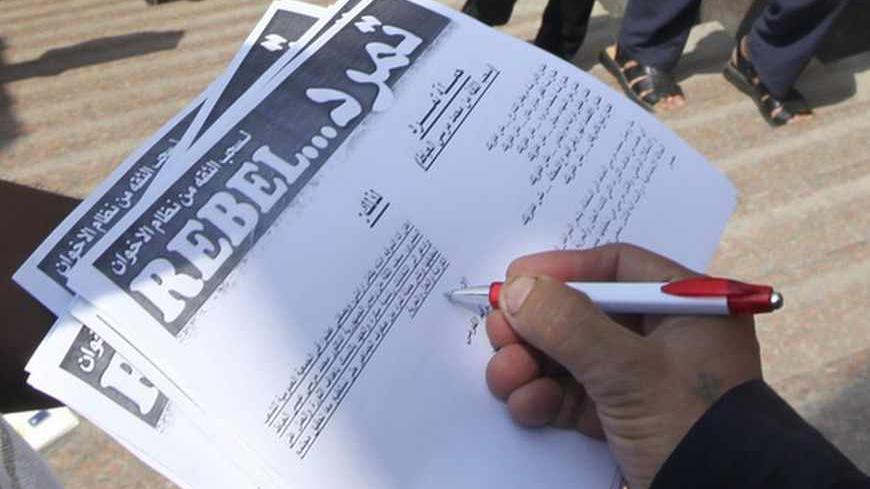 A man signs a "Tamarod" document at Tahrir square in Cairo May 16, 2013. A campaign named "Tamarod", meaning "Rebel", calling for the ouster of Egyptian President Mohamed Mursi and for early presidential elections has gathered over two million signatures since its launch nearly two weeks ago in Egypt, organisers said.      REUTERS/Mohamed Abd El Ghany  (EGYPT - Tags: POLITICS CIVIL UNREST) - RTXZP6G