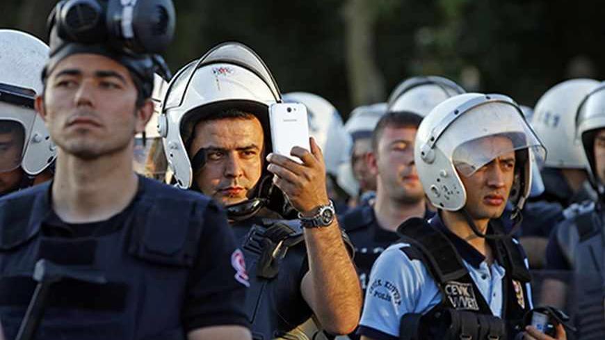 A riot policeman uses a mobile phone to film protesters at Taksim Square in Istanbul June 22, 2013. Turkish riot police fired water cannon to clear thousands of protesters from Istanbul's Taksim Square on Saturday, the first such confrontation there in nearly a week.   REUTERS/Marko Djurica (TURKEY  - Tags: POLITICS CIVIL UNREST)   - RTX10X89