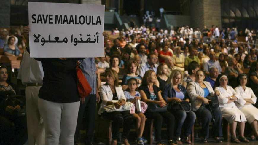 A Syrian woman holds a banner for saving Maaloula while Lebanese and Syrian Christian Maronites pray for peace in Syria, in Harisa, Jounieh September 7, 2013. REUTERS/Hasan Shaaban (LEBANON - Tags: POLITICS RELIGION) - RTX13C2S