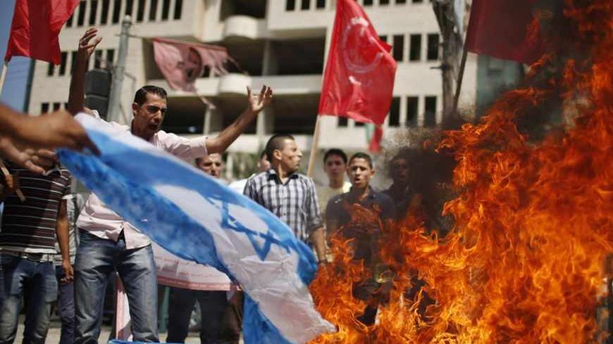 Supporters of Palestinian leftist parties burn a replica Israeli flag during a rally calling for the cancellation of the Oslo peace agreement and the end of the latest round of peace talks with Israel in Gaza City September 15, 2013. The Oslo peace accord was signed by the Palestinian Liberation Organisation (PLO) and Israel in 1993 and was meant to pave the way to a permanent peace between the Palestinians and Israel.  REUTERS/Mohammed Salem (GAZA - Tags: POLITICS CIVIL UNREST) - RTX13LZB