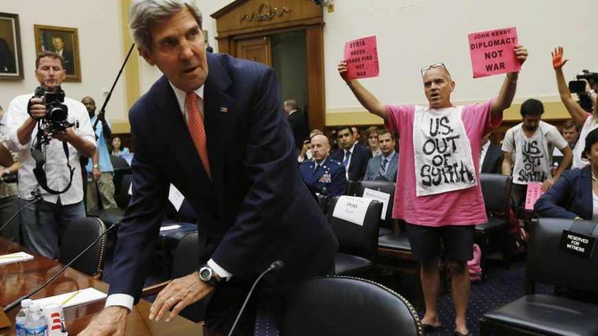 U.S. Secretary of State John Kerry faces protesters against a military strike in Syria, as he arrives at a U.S. House Foreign Affairs Committee hearing on Syria on Capitol Hill in Washington, September 4, 2013. The U.S. Senate Foreign Relations Committee will likely vote later on Wednesday on a draft resolution authorizing the use of military force in Syria, several members of the panel said. REUTERS/Jason Reed  (UNITED STATES - Tags: POLITICS MILITARY CONFLICT) - RTX13780