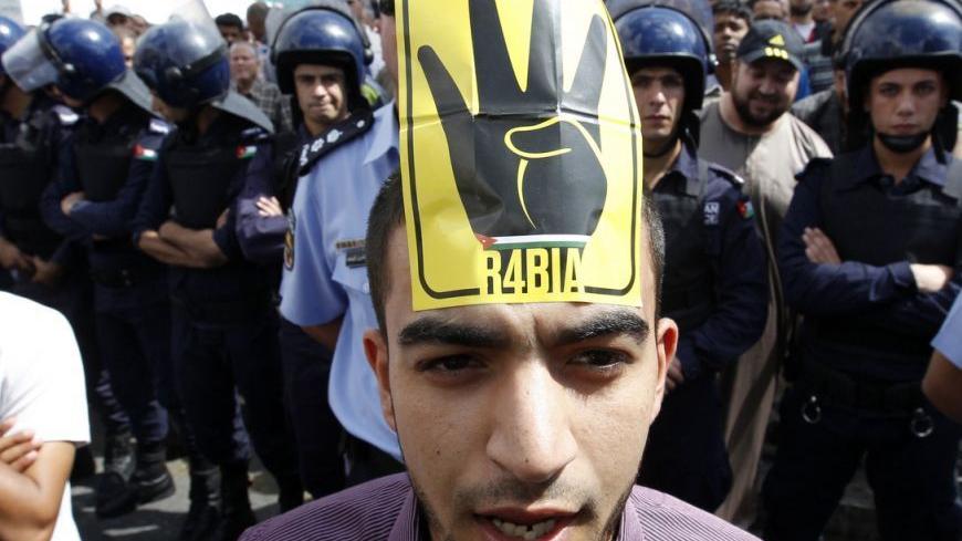 A supporter of Jordan's opposition parties wearing a sign on his forehead shouts slogans demanding freedom for political prisoners, political and economic reforms, and access to government corruption cases during a demonstration after Friday prayers in Amman October 4, 2013. Anti-government protesters across the region have been using the four-fingered salute on a yellow background, which represents those who were killed in Cairo's al-Rabia Square in Egypt in August, as a tacit statement of opposition to th