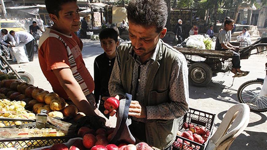 A man cleans apples for sale in the city of Aleppo October 5, 2013. REUTERS/Muzaffar Salman (SYRIA - Tags: FOOD SOCIETY BUSINESS) - RTR3FMF8