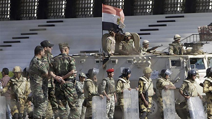 Military personnel stand next to an armoured personnel carrier during a protest near Al-Azhar University in Cairo October 20, 2013. Egyptian security forces fired bird shot and tear gas to prevent supporters of deposed Islamist President Mohamed Mursi from marching on Sunday to the site of a protest camp at Rabaa al-Adaweya mosque that was destroyed two months ago, a Reuters witness said. The crowd of about 500 people were students from Al-Azhar University. REUTERS/Mohamed Abd El Ghany (EGYPT  - Tags: POLIT