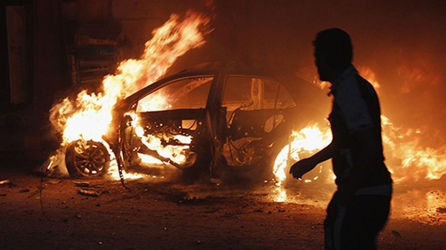 A man looks at a car on fire at the site of a bomb attack in Baghdad October 7, 2013. Bombs exploded across the Iraqi capital Baghdad on Monday, killing at least 22 people, police said. Five of the six blasts were in mainly Shi'ite Muslim districts, but there was also an explosion in the predominantly Sunni Muslim neighborhood of Doura.  REUTERS/Ahmed Saad (IRAQ - Tags: POLITICS CIVIL UNREST TPX IMAGES OF THE DAY) - RTX142ZK