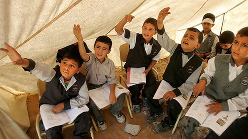 Palestinian boys study inside a tent outside their destroyed classroom at al-Arkam school in Gaza October 1,2005. Their school in Gaza was destroyed by missiles from an Israeli warplane last Sunday. REUTERS/Suhaib Salem PP05100031 - RTR18ICS
