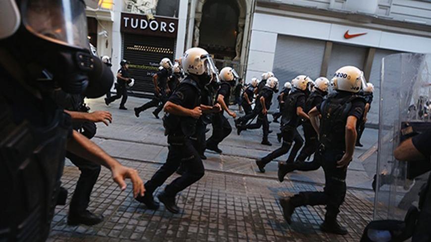 Riot police officers run after demonstrators on Istiklal Street in central Istanbul July 13, 2013. Turkish police fired water cannon and tear gas on Saturday to disperse hundreds of protesters who gathered to march to Gezi Park, which has been at the heart of fierce unrest against Prime Minister Erdogan's rule. Protesters scattered, running into sidestreets where police pursued them, before starting to regroup on Istiklal Street, metres from the main Taksim Square. REUTERS/Umit Bektas (TURKEY - Tags: POLITI