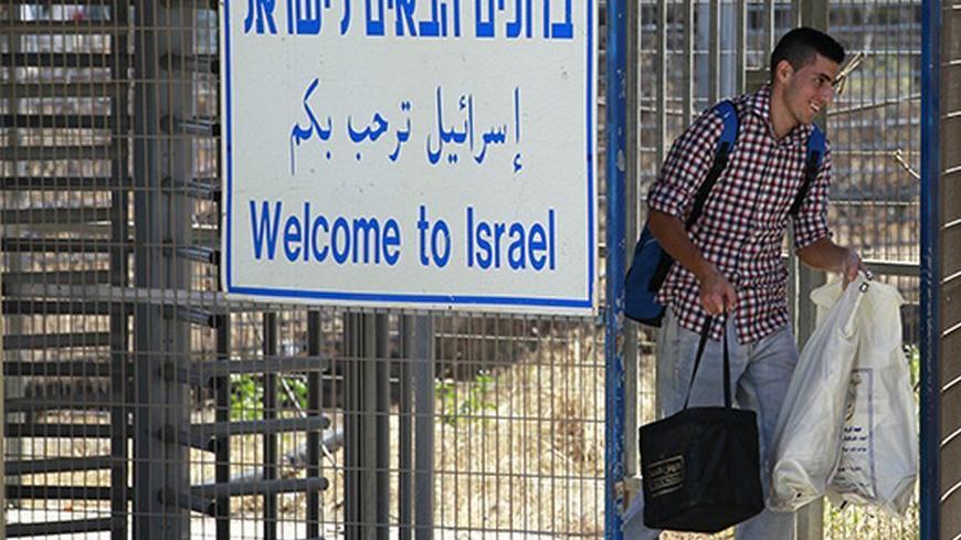 A student studying in Syria carries his luggage as he crosses through the Quneitra border crossing between Israel and Syria, as seen from the Israeli side of the Israeli-occupied Golan Heights July 11, 2013. A spokesperson for the International Committee of the Red Cross said 23 students, mostly from the Druze community, crossed into the Golan Heights from Syria at Quneitra on Thursday. REUTERS/Baz Ratner (POLITICS SOCIETY) - RTX11JTW