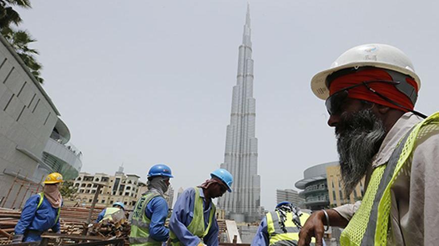Labourers work near the Burj Khalifa, the tallest tower in the world, in Dubai May 9, 2013. REUTERS/Ahmed Jadallah (UNITED ARAB EMIRATES - Tags: BUSINESS CONSTRUCTION) - RTXZFXJ
