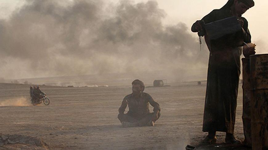 A man works at a makeshift oil refinery site in al-Mansoura village in Raqqa's countryside May 5, 2013. Many civilians in the village who lost their jobs due to the Syrian conflict are making a living by refining crude oil to extract useful fuel such as gasoline and kerosene for sale. Picture taken May 5, 2013. REUTERS/Hamid Khatib (SYRIA - Tags: CONFLICT ENERGY BUSINESS EMPLOYMENT) - RTXZIAB