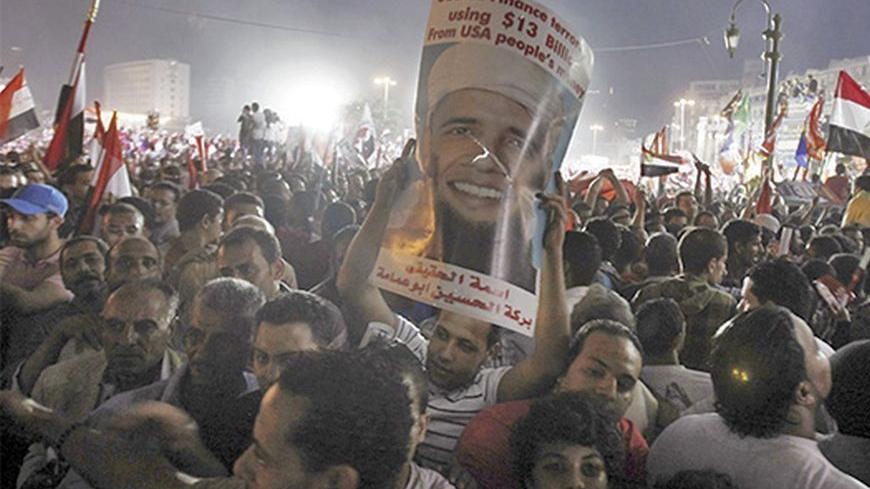 Anti-Mursi protesters cheer and hold up a poster depicting U.S. president Barack Obama with a beard at Tahrir square, where protesters gathered for a mass protest to support the army, in Cairo, July 26, 2013. Egypt's army is recasting the country's political drama, giving popular army chief Abdel Fattah al-Sisi the starring role in a change with echoes of the past that could undermine democracy in the Arab world. Picture taken July 26, 2013. REUTERS/Amr Abdallah Dalsh  (EGYPT - Tags: POLITICS CIVIL UNREST M