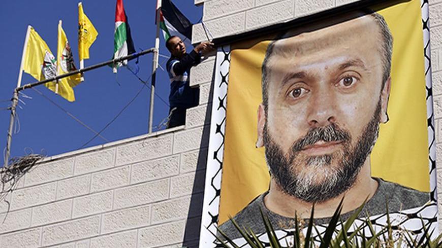 A relative hangs a banner depicting Palestinian prisoner Moses Qar'an outside his house, in the West Bank city of Ramallah October 28, 2013.  Israel is to release 26 Palestinian prisoners in the second stage of a deal brokered by the U.S. in July that brought about the resumption of peace talks.  REUTERS/Mohamad Torokman (WEST BANK - Tags: CIVIL UNREST POLITICS) - RTX14R4A