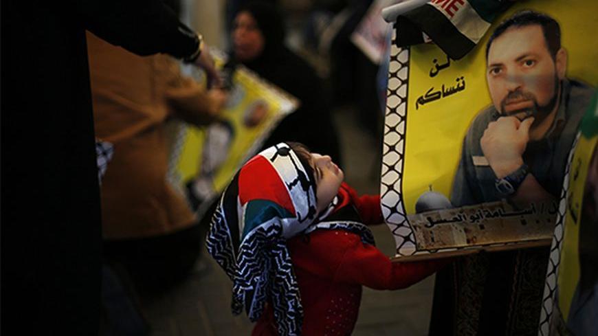 A Palestinian girl looks at a picture of a jailed relative during a protest demanding the release of all Palestinian prisoners held in Israeli jails, in Gaza City October 28, 2013. Israel is to release 26 Palestinian prisoners in the second stage of a deal brokered by the U.S. in July that brought about the resumption of peace talks. The words on top of the poster read, "We will not forget you".            REUTERS/Suhaib Salem (GAZA - Tags: POLITICS CIVIL UNREST CONFLICT TPX IMAGES OF THE DAY) - RTX14R3N