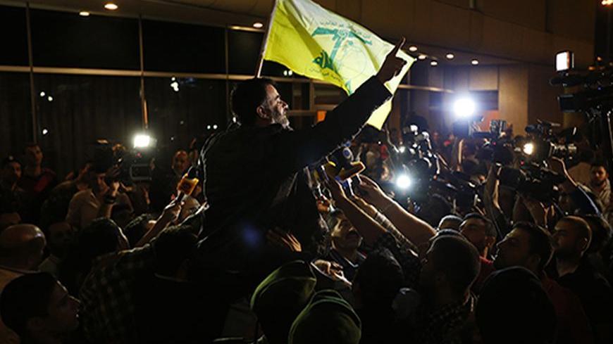 One of the nine newly released Lebanese hostages, who were held by rebels in northern Syria, carries a Hezbollah flag as he is welcomed by his relatives upon his arrival at Beirut international airport, October 19, 2013. A plane with nine Lebanese hostages freed from northern Syria landed safely in Beirut on Saturday night, witnesses said, nearly a year and a half after the men were captured by Syrian rebels near the Turkish border. REUTERS/Mohamed Azakir  (LEBANON - Tags: POLITICS CIVIL UNREST) - RTX14H60