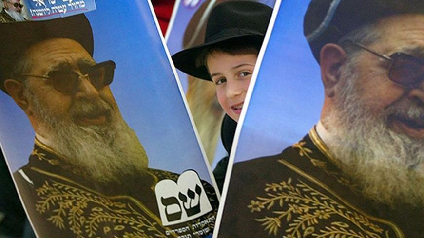 A YOUNG SUPPORTER OF SHAS PARTY SMILES BEHIND POSTERS OF RABBI JOSEF
OVADIA DURING ELECTIONS RALLY IN ASHDOD. - RTRGS9Y