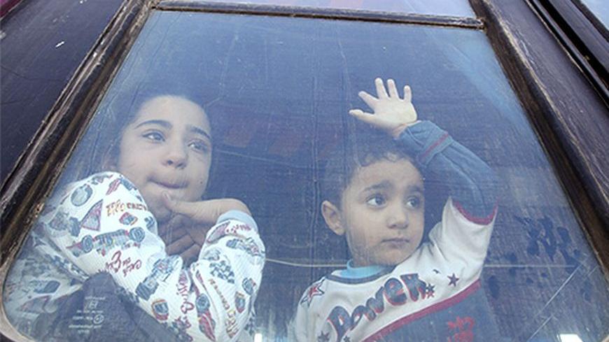 Palestinian children hoping to cross into Egypt, look out of a bus window at the Rafah crossing between Egypt and the southern Gaza Strip October 8, 2013. Egypt partially reopened its border crossing with the Gaza Strip for four days on Tuesday for the humanitarian needs of patients seeking treatment, and students studying outside of Gaza, a Palestinian official said. REUTERS/Ahmed Zakot (GAZA - Tags: POLITICS TPX IMAGES OF THE DAY SOCIETY IMMIGRATION) - RTX143OA