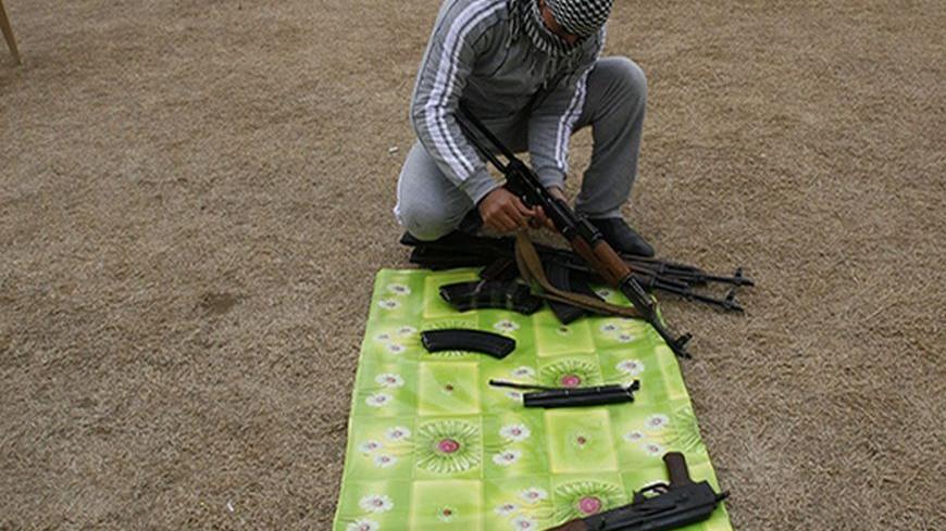 A weapons dealer checks AK-47 rifles before selling it to smugglers transferring it to Syria, at his house near the city of Mosul, 390km (240 miles) north of Baghdad, February 16, 2012. The weapons dealers sell a rifle for about $1000.  REUTERS/Stringer (IRAQ - Tags: CONFLICT) - RTR2XY8B