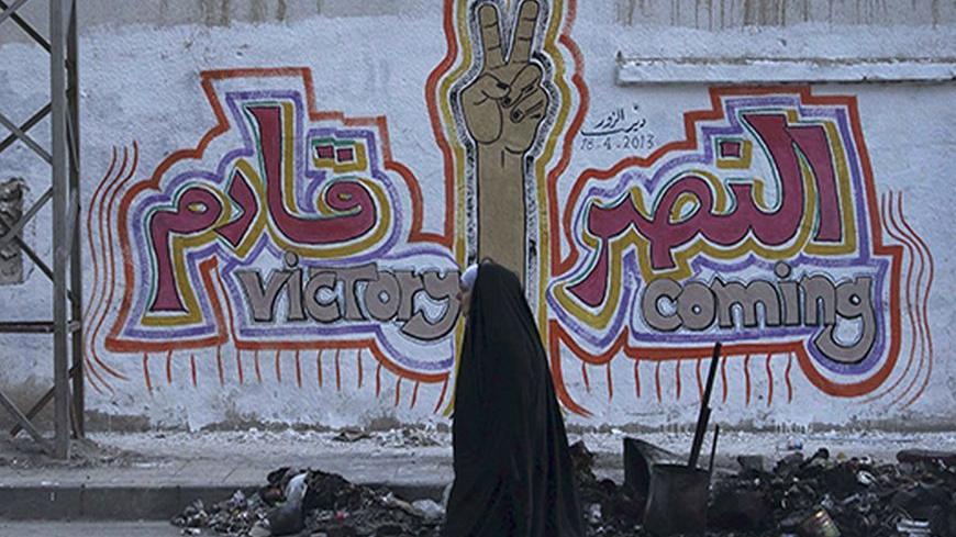 A woman walks along a street past graffiti that reads "Victory coming" in Deir al-Zor April 20, 2013. Picture taken April 20, 2013. REUTERS/Khalil Ashawi  (SYRIA - Tags: POLITICS CIVIL UNREST SOCIETY) - RTXYUF5
