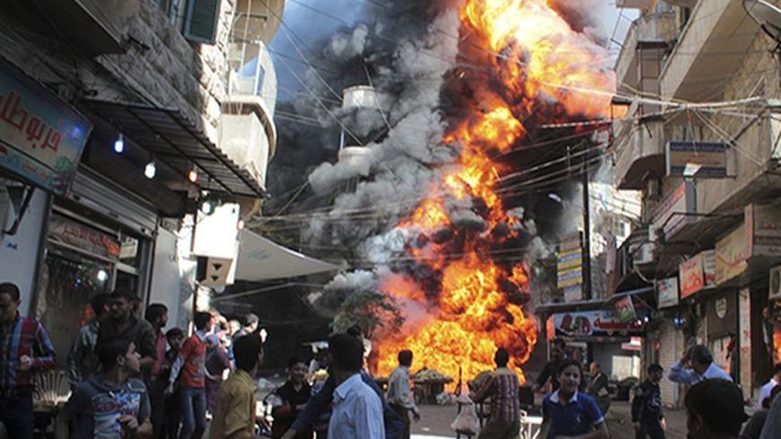 Residents run from a fire at a gasoline and oil shop in Aleppo's Bustan Al-Qasr neighbourhood October 20, 2013. Witnesses said the fire was caused by a bullet fired by a sniper loyal to Syrian President Bashar al-Assad at the Karaj al-Hajez crossing, a passageway separating Aleppo's Bustan al-Qasr, which is under the rebels' control and Al-Masharqa neighborhood, an area controlled by the regime.  REUTERS/Haleem Al-Halabi (SYRIA - Tags: DISASTER TPX IMAGES OF THE DAY) - RTX14HWX