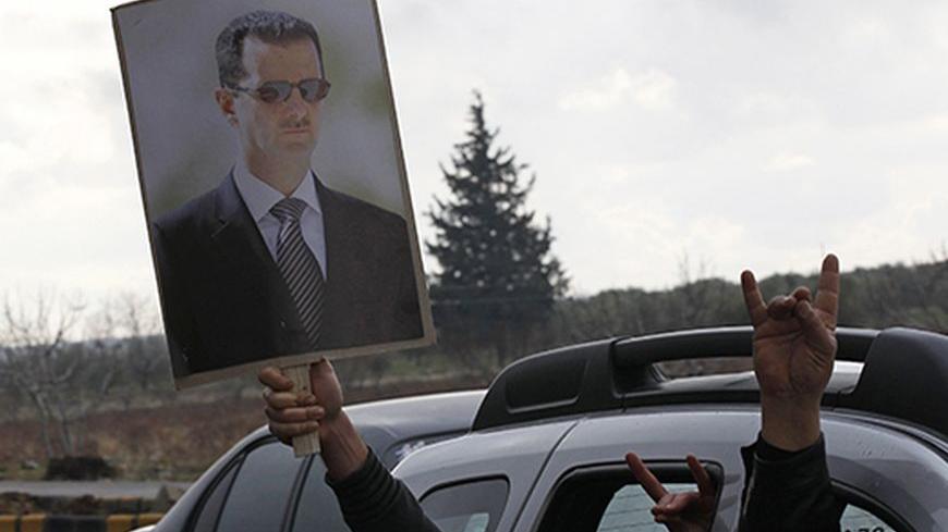 Turkish men flash nationalist gestures while carrying a poster of Syria's President Bashar al-Assad as they drive to the Oncupinar border crossing during a demonstration in support of Syrian government near the Turkish-Syrian border town of Kilis, Gaziantep province, January 12, 2012. REUTERS/Umit Bektas (TURKEY - Tags: POLITICS CIVIL UNREST) - RTR2W6OM