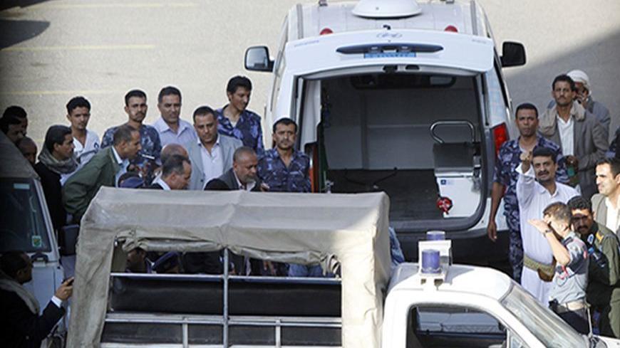 Policemen and ambulance personnel gather outside a supermarket after a shooting in Sanaa October 6, 2013. Gunmen shot dead a German employee of the German embassy in Yemen's capital Sanaa on Sunday, Yemeni security officials said.     REUTERS/Mohamed al-Sayaghi (YEMEN - Tags: CRIME LAW) - RTR3FNRH