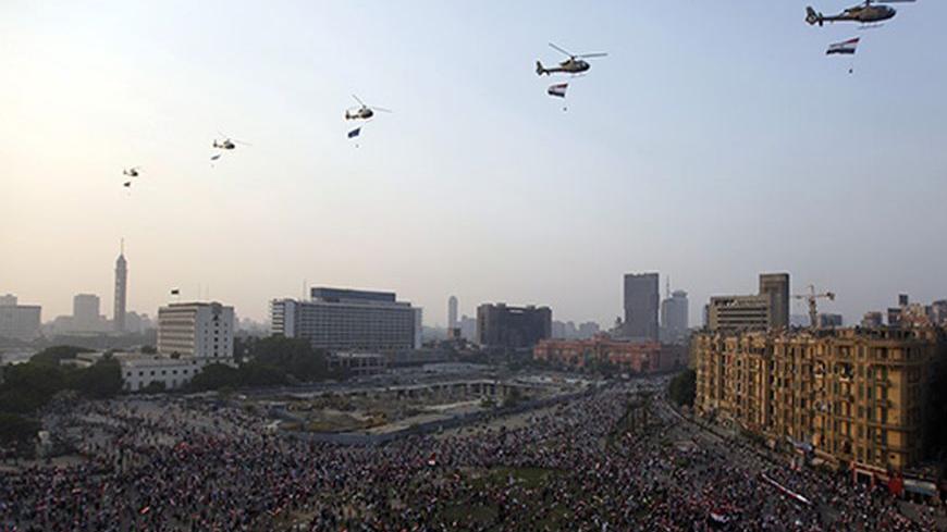 Military helicopters are seen flying over while people gather at Tahrir Square to celebrate the anniversary of an attack on Israeli forces during the 1973 war, in Cairo October 6, 2013. REUTERS/Mohamed Abd El Ghany (EGYPT - Tags: POLITICS ANNIVERSARY MILITARY) - RTR3FNYZ