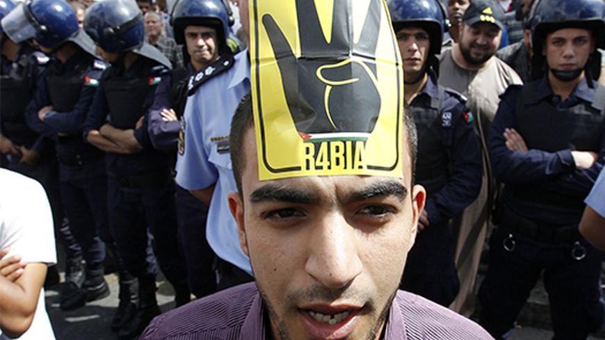 A supporter of Jordan's opposition parties wearing a sign on his forehead shouts slogans demanding freedom for political prisoners, political and economic reforms, and access to government corruption cases during a demonstration after Friday prayers in Amman October 4, 2013. Anti-government protesters across the region have been using the four-fingered salute on a yellow background, which represents those who were killed in Cairo's al-Rabia Square in Egypt in August, as a tacit statement of opposition to th