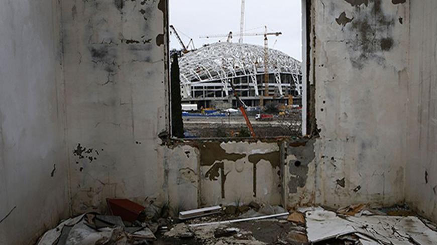 A picture shot through the window of a house that has to be torn down as it is within the perimeters of the Olympic Park shows the Olympic stadium for the Sochi 2014 Winter Olympics at the Olympic Park in Adler, near Sochi February 18, 2013. Although many complexes and venues in the Black Sea resort of Sochi mostly resemble building sites that are still under construction, there is nothing to suggest any concern over readiness. Construction will be completed by August 2013 according to organizers. The Sochi