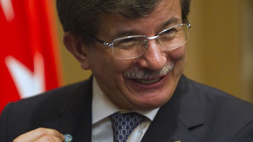 Turkey's Foreign Minister Ahmet Davutoglu shows a Shanghai Cooperation Organisation (SCO) pin after a signing ceremony granting Turkey a partner status in SCO, in Almaty April 26, 2013.  REUTERS/Shamil Zhumatov  (KAZAKHSTAN - Tags: POLITICS BUSINESS) - RTXZ0SB