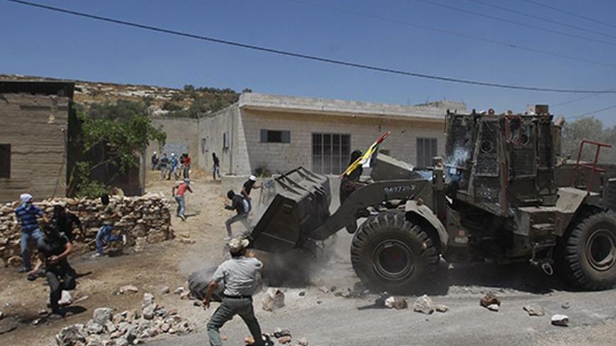 Palestinian protesters run away as an Israeli military bulldozer clears a road block placed by the protesters during clashes at a demonstration against the nearby Jewish settlement of Kdumim, in the West Bank village of Kfar Kadum, near Nablus June 8, 2012. REUTERS/Mohamad Torokman (WEST BANK - Tags: POLITICS CIVIL UNREST) - RTR33A9S