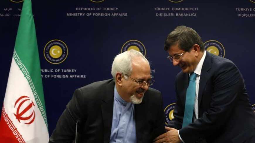 Turkish Foreign Minister Ahmet Davutoglu (R) helps Iranian Foreign Minister Mohammad Javad Zarif to stand during a news conference in Ankara November 1, 2013. Turkey and Iran said on Friday they had common concerns about the increasingly sectarian nature of Syria's civil war, signalling a thaw in a key Middle Eastern relationship strained by stark differences over the conflict. Davutoglu expressed his appreciation to Zarif at the start of the news conference for travelling to Turkey despite suffering from b