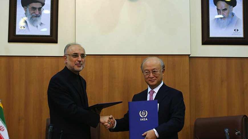 Head of Iran's Atomic Energy Organisation Ali Akbar Salehi (L) and International Atomic Energy Agency (IAEA) Director General Yukiya Amano, shakes hands under portraits of Iran's supreme leader, Ayatollah Ali Khamenei (L) and Iran's founder of Islamic Republic, Ayatollah Ruhollah Khomeini (R), following their meeting in Tehran on November 11, 2013. Amano arrived in the Iranian capital to discuss Iran's nuclear programme after top world diplomats fail to clinch a long-sought deal to curb Tehran's nuclear act