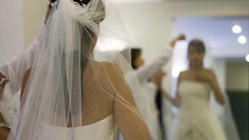 An Iranian dress designer checks the fit of a veil on a bride at a high fashion studio in north Tehran October 2, 2007. Wearing the all-enveloping chador (veil) or a headscarf and loose-fitting full-length coat is obligatory under Sharia law, imposed after the 1979 Islamic revolution. Offenders face fines, whipping or jail. But that has not stopped image-conscious Iranian women and a growing number are going under the knife for new noses, tummy tucks, liposuction, lifting eyelids or breast augmentation. Pic