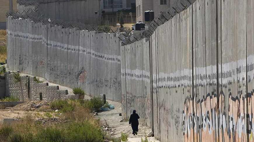 A Palestinian woman walks along the controversial Israeli barrier in al-Ram in the West Bank on the outskirts of Jerusalem July 6, 2010. REUTERS/Baz Ratner (WEST BANK - Tags: POLITICS) - RTR2G4VG