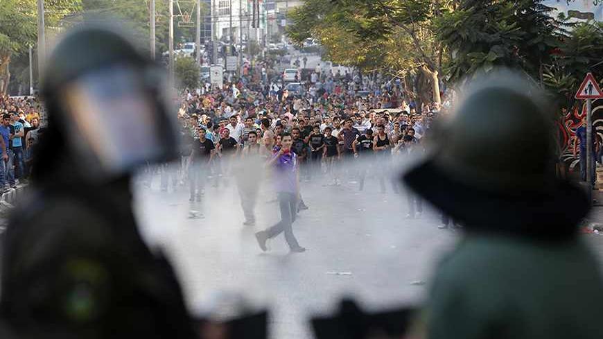 Palestinians security officers stand in front of protesters during clashes at a demonstration against high living costs and the government in the West Bank city of Hebron September 10, 2012. Palestinian youths attacked a local police station and other government buildings in Hebron on Monday as protests against the rising cost of living in the occupied West Bank turned increasingly violent. REUTERS/Darren Whiteside (WEST BANK - Tags: POLITICS CIVIL UNREST BUSINESS) - RTR37S1J