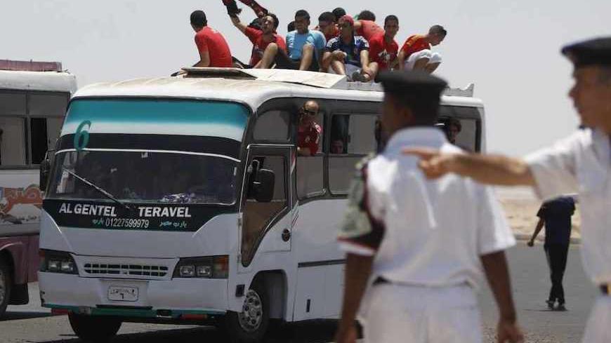Ultras, or hardcore fans, of Egypt's Al Ahly sit atop a bus as riot police cordon off the road in front of the buses of Ultras before the derby CAF Champions League soccer match between Egypt's Zamalek and Al Ahly at El-Gouna stadium in Hurghada, about 464 km (288 miles) from the capital Cairo July 24, 2013.  REUTERS/Amr Abdallah Dalsh  (EGYPT - Tags: SPORT SOCCER CIVIL UNREST) - RTX11WZG