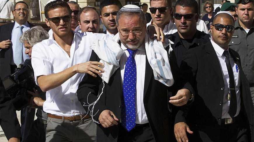 Former Israeli Foreign Minister Avigdor Lieberman (C) wears a prayer shawl as he arrives at the Western Wall, Judaism's holiest site, in Jerusalem's Old City, following his acquittal in a corruption trial November 6, 2013. Israeli Prime Minister Benjamin Netanyahu welcomed Lieberman back to government on Wednesday after the ultra-nationalist politician was acquitted of corruption charges. REUTERS/Ronen Zvulun (JERUSALEM - Tags: POLITICS CRIME LAW RELIGION) - RTX1523P