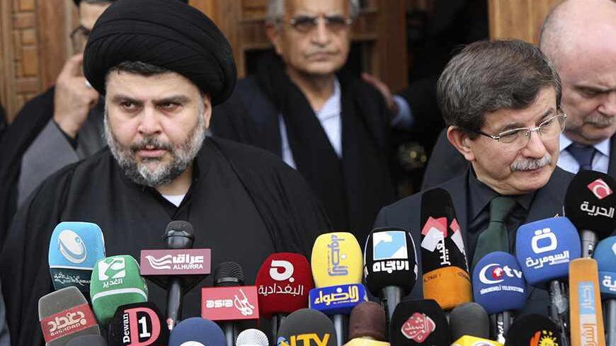 Iraqi Shi'ite radical cleric Muqtada al-Sadr (L) attends a joint news conference with Turkish Foreign Minister Ahmet Davutoglu (R) during his visit to Najaf, 160km (100 miles) south of Baghdad, November 11, 2013.  REUTERS/Alaa Al-Marjani (IRAQ - Tags: POLITICS) - RTX1597Z