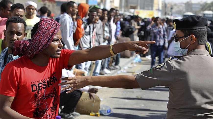 An Ethiopian worker argues with a member of the Saudi security forces as he waits with his countrymen to be repatriated in Manfouha, southern Riyadh, November 11, 2013. Thousands of mostly African workers gathered in Riyadh on Sunday seeking repatriation after two people were killed in overnight rioting that followed a visa crackdown by Saudi authorities. One of those killed was a Saudi, said a government statement, and the other was not identified. An Ethiopian man was killed in a visa raid last week. Ethi