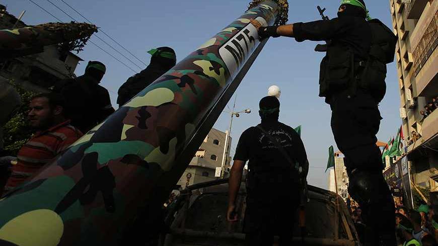 Palestinian Hamas militants stand next to M-75 home made rocket as they take part in a military parade marking the first anniversary of the eight-day conflict with Israel, in Gaza City November 14, 2013. Eight days of Israeli air strikes on Gaza and cross-border Palestinian rocket attacks in November last year ended in an Egyptian-brokered truce agreement calling on Israel to ease restrictions on the territory. REUTERS/Suhaib Salem (GAZA - Tags: POLITICS ANNIVERSARY CONFLICT MILITARY) - RTX15DKU