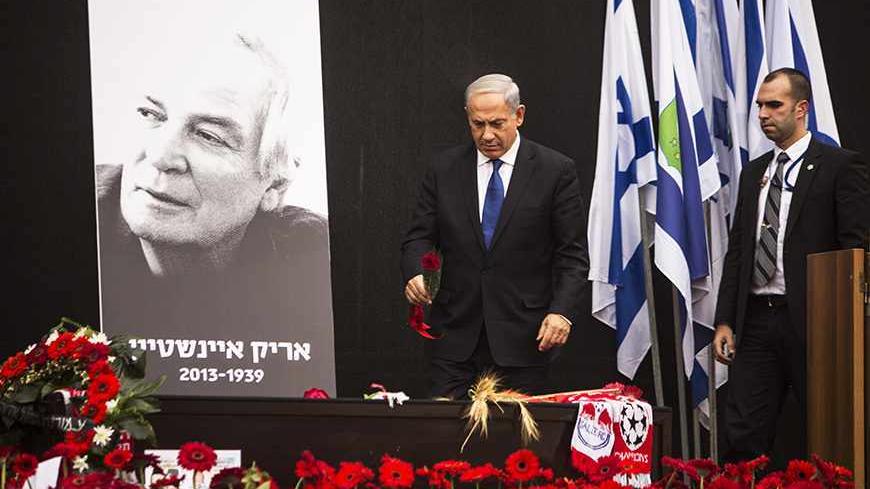 Israeli Prime Minister Benjamin Netanyahu (C) lays a rose on the coffin of Israeli singer Arik Einstein, depicted in the placard, during a memorial ceremony before his funeral at Rabin square in Tel Aviv November 27, 2013. For many Israelis, nothing symbolised home more than singer Einstein, and on Wednesday a nation mourned the death of its king of cool. Einstein died of a ruptured aneurysm on Tuesday night at the age of 74. REUTERS/Nir Elias (ISRAEL - Tags: ENTERTAINMENT OBITUARY SOCIETY) - RTX15UZ9