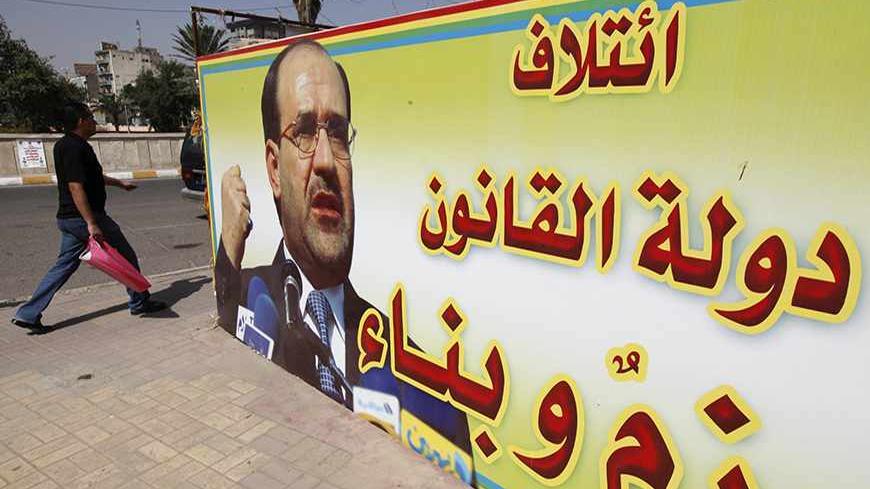 An Iraqi walks past a provincial elections campaign billboard in Baghdad, April 18, 2013. Iraq will hold its provincial elections on Saturday. The billboard reads, "coalition of state of law, determination and construction". REUTERS/Mohammed Ameen (IRAQ - Tags: SOCIETY POLITICS ELECTIONS) - RTXYQSD