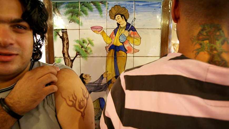 Two men display tattoos on their arm and neck while standing in front of an Iranian painting at a shopping centre in northern Tehran September 21, 2006. REUTERS/Morteza Nikoubazl (IRAN) - RTR1HM9D