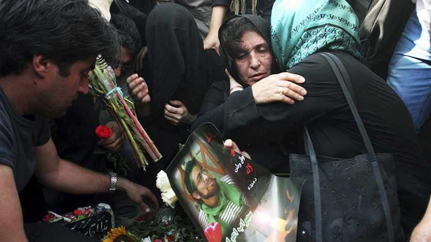 Relatives of a victim of recent clashes hold his picture as they cry over the grave of Neda Agha-Soltan at Tehran's Behesht-e Zahra cemetery July 30, 2009. Baton-wielding Iranian police fired tear gas on Thursday and arrested protesters mourning the young woman killed in post-election violence who has become a symbol for the opposition to Tehran's hardline leaders.  REUTERS/Reuters via Your View (IRAN CONFLICT POLITICS) - RTR268R8