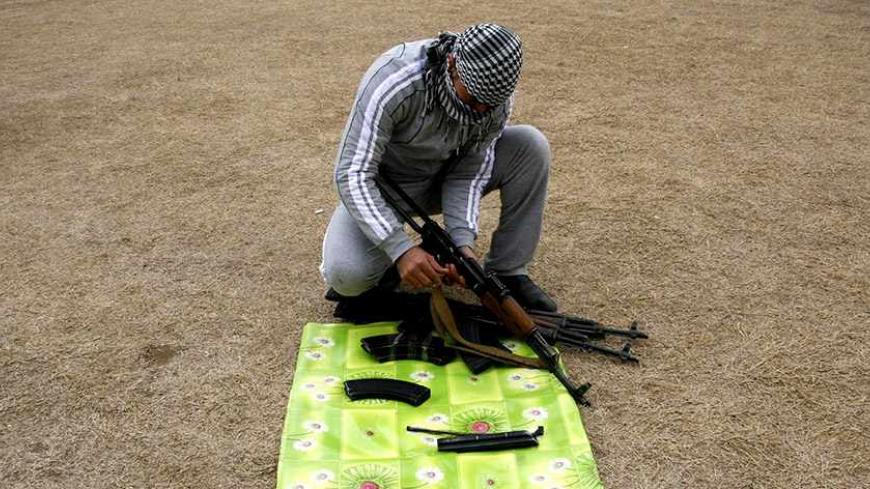 A weapons dealer checks AK-47 rifles before selling it to smugglers transferring it to Syria, at his house near the city of Mosul, 390km (240 miles) north of Baghdad, February 16, 2012. The weapons dealers sell a rifle for about $1000.  REUTERS/Stringer (IRAQ - Tags: CONFLICT) - RTR2XY8B